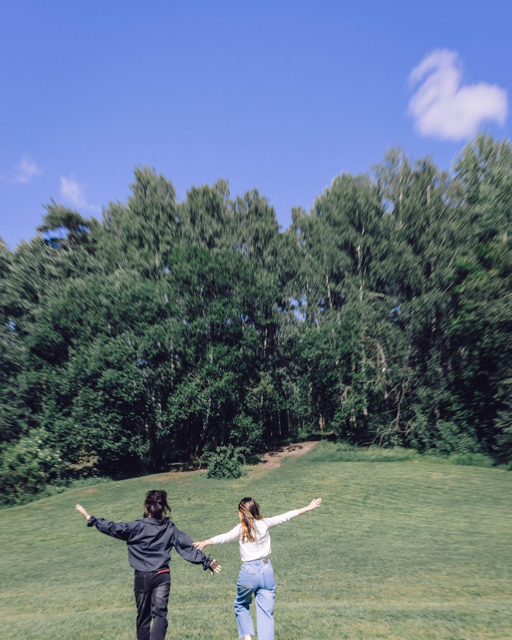 Two friends running across a green field