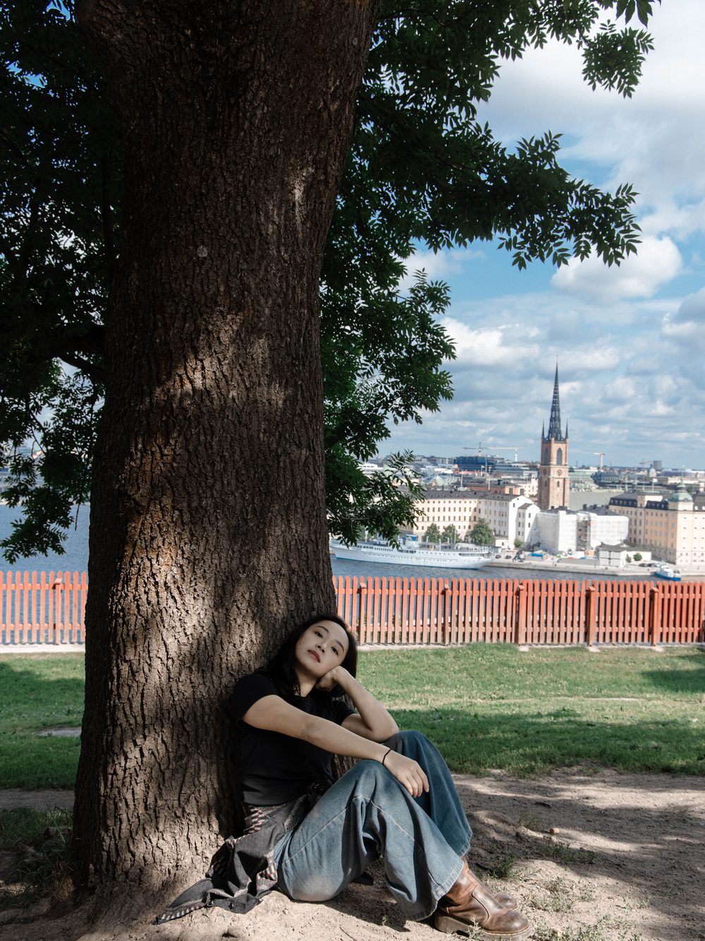 Resting under a big tree, the city across the water